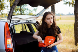 Girl standing with emergency kit outside her car